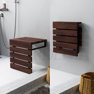 May include: A dark brown wooden shower bench with a slatted seat design. The bench is mounted on a black metal frame. The image also shows a matching wall-mounted bench in the folded position.