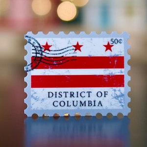 May include: A rectangular stamp featuring the flag of the District of Columbia. The design includes red stripes and three red stars on a white background. The text "DISTRICT OF COLUMBIA" is printed at the bottom, with a 50¢ value.