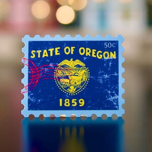 May include: A blue and yellow stamp with the text "State of Oregon" and "50c". The stamp features a yellow image of the state seal of Oregon, which includes a shield with a beaver, a wheat sheaf, and a mountain range. The stamp also includes the year "1859".