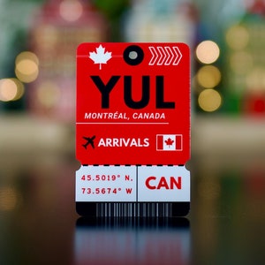 May include: Red and white airport arrival tag with the code YUL, Montreal, Canada, and the coordinates 45.5019° N, 73.5674° W.