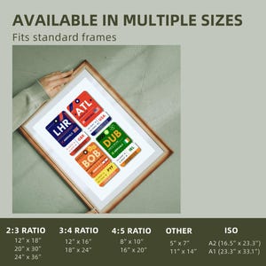 May include: A framed print featuring colorful travel-themed designs resembling luggage tags. The tags display airport codes like LHR, ATL, DUB, and BOB, with country flags and the text "ARRIVALS." The print is available in multiple sizes, including 12" x 18" and 20" x 30".