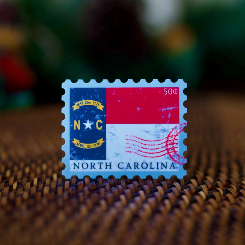 May include: A blue and red postage stamp featuring the North Carolina state flag with the text "NORTH CAROLINA" and "50c".