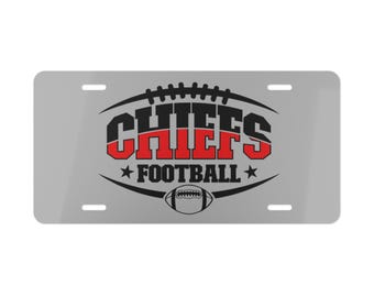 May include: A silver license plate with the word "CHIEFS" in black and red, with a football graphic above and below the text. The word "FOOTBALL" is below the text, with stars on either side.