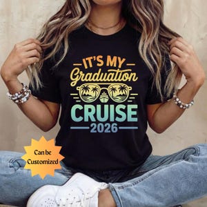 May include: Black t-shirt with the text "IT'S MY GRADUATION CRUISE 2026" in a gradient of yellow, orange, and blue. The design includes sunglasses with palm trees and a cruise ship. The words "Can be Customized" are also visible.