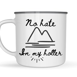 Könnte beinhalten: Weiße Email Tasse mit grauem Rand. Die Tasse hat ein schwarzes handgeschriebenes Design, das "No hate in my holler" mit einer Zeichnung von zwei Bergen und einem See sagt.