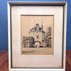 May include: A framed ink drawing on tan paper depicting a stone gatehouse with a central archway, a small tower, and adjacent buildings. The artwork is enclosed in a white textured mat and a simple white frame with a thin dark inner border.