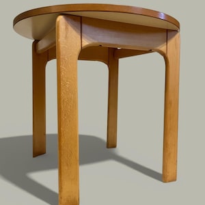 May include: A small, light-coloured wooden side table with a round top. The table has four straight legs and a curved apron. The top is approximately 51 cm in diameter. The table is made of light-coloured wood with a natural finish.