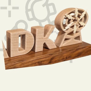 May include: A wooden sculpture featuring the letters "DK" and a stylized radio tower with lightning bolt accents. The letters and tower are light-colored, set on a dark wood base. The design is a unique decorative item.