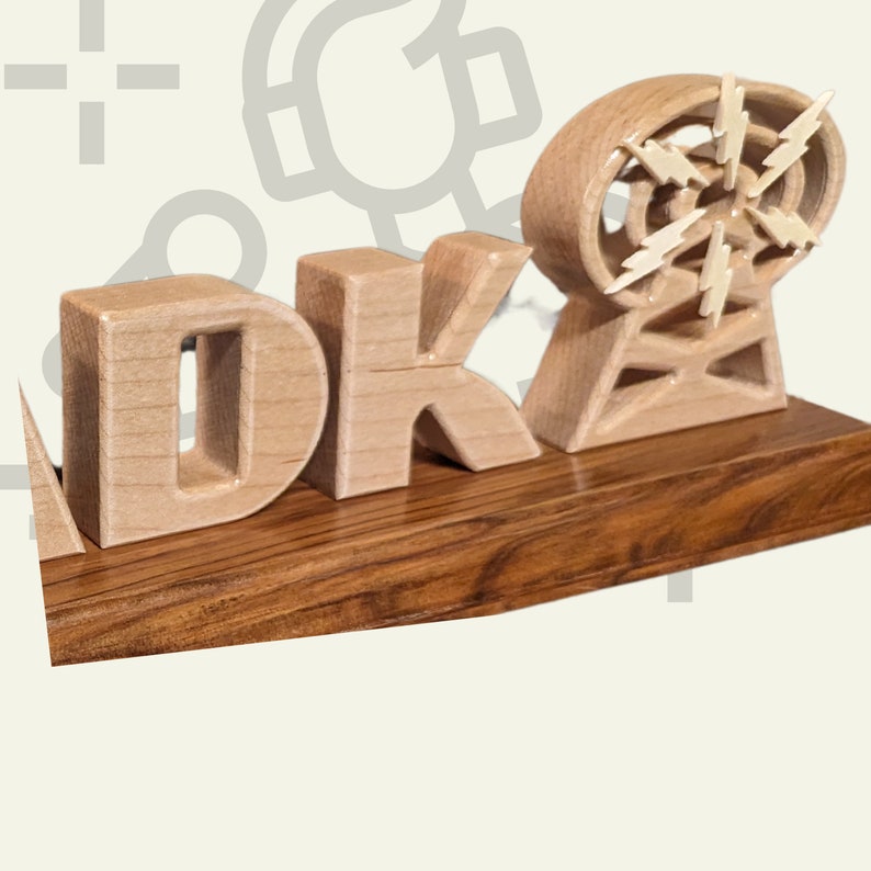 May include: A wooden sculpture featuring the letters "DK" and a stylized radio tower with lightning bolt accents. The letters and tower are light-colored, set on a dark wood base. The design is a unique decorative item.