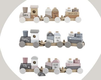 May include: Three wooden toy trains with personalised names and birth details. Each train has a grey, white and brown colour scheme and includes blocks with the child's name, birth date, time, length and weight.