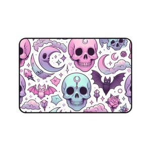 May include: A rectangular mousepad with a repeating pattern of pastel skulls, bats, moons, stars, and crystals on a white background. The skulls are in shades of pink, blue, and purple. The bats have pink wings, and the moons are purple.