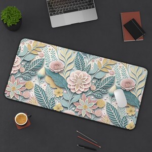 May include: A floral design desk mat featuring a repeating pattern of pastel-colored flowers and leaves. The mat includes pink, blue, and yellow elements, with a white background. A computer mouse rests on the mat.