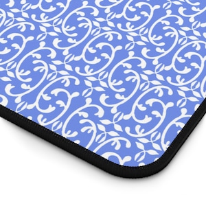 May include: A blue and white patterned mousepad with a black border. The design features a repeating floral scroll pattern in white against a light blue background. The mousepad is rectangular.