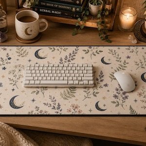 Peut inclure: Un tapis de bureau rectangulaire au fond crème orné d'un motif répétitif de croissants de lune bleu foncé, d'étoiles dorées et d'illustrations botaniques variées, incluant des fougères, des fleurs sauvages et des brindilles aux tons doux.