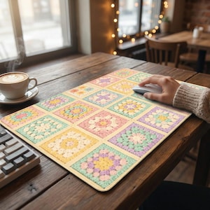May include: A rectangular mouse pad featuring a colorful patchwork design. The pad is made up of squares with pastel floral patterns in shades of yellow, pink, green, and purple. A computer mouse rests on the pad.