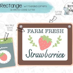 May include: A rectangular cookie cutter with rounded corners, featuring a "Farm Fresh Strawberries" design. The image includes a strawberry graphic and text, along with a smaller card with a strawberry illustration and the text "Multiple ways to ice."