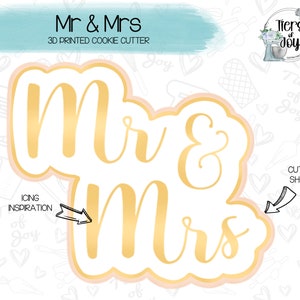 May include: A 3D printed cookie cutter in the shape of the words "Mr & Mrs" in a gold script font. The cutter is on a white background with a pink outline.