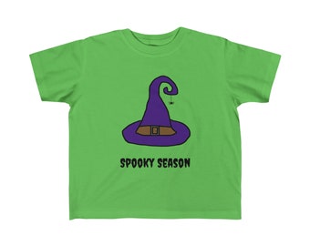 Könnte beinhalten: Ein grünes T-Shirt mit einem lila Hexenhut und dem Text "Spooky Season" darauf.