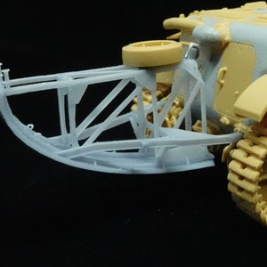May include: A close-up of a white plastic model tank with a detailed track system and a rear-mounted spare tire.
