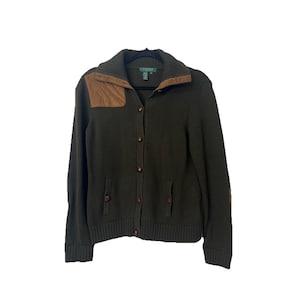 以下が含まれることがあります： 肩と肘に茶色のスエードパッチが付いた、濃いオリーブグリーンのカーディガン。ボタン留めのセーターは、リブ編みの袖口と2つのフロントポケットが付いています。襟は濃い緑色です。