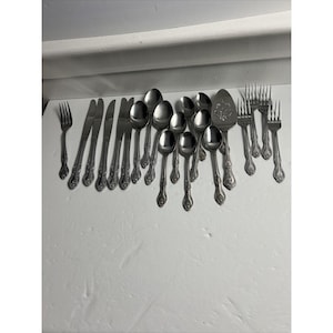 May include: A set of silverware with ornate handles, including forks, spoons, and a serving knife. The silverware is made of stainless steel and has a polished finish.