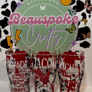 May include: Three clear pint glasses with red and black designs. Each glass has a name in white lettering. One glass says "Amanda" with "Happy Christmas" below. The other glasses say "Jacob" and "Macaule".