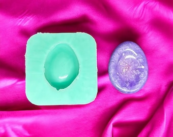 May include: A green silicone mold for making resin crafts, next to a finished purple resin piece with glitter.