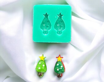May include: A green silicone mould with two Christmas tree shapes. Two green and red Christmas tree ornaments with gold stars.