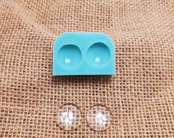 May include: A light blue silicone mold with two round cavities for making resin earrings. Two clear resin earrings are shown next to the mold.