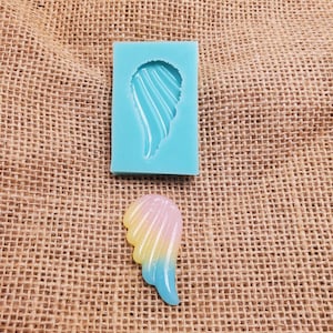May include: A blue silicone mold for making resin wings. The mold is shown with a finished resin wing that is a gradient of yellow, pink, and blue.