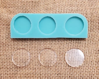 May include: A turquoise silicone mold with three round cavities for making resin crafts. Three clear round resin blanks are shown next to the mold.