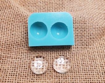 May include: A light blue silicone mold with two round cavities for making resin crafts. Two clear resin cabochons are shown next to the mold.