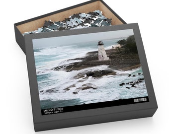 May include: A 500 piece jigsaw puzzle featuring a lighthouse on a rocky coast with crashing waves. The puzzle box is open and shows the completed puzzle image. The box has the text "16x20 Puzzle 500 pcs Ages 9+"