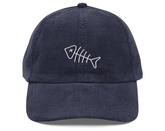 Op de afbeelding: Een donkerblauwe corduroy baseballpet met een wit geborduurd vis skelet ontwerp.