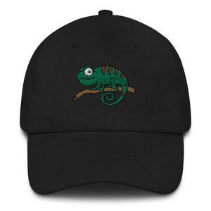 Può includere: Un cappello da baseball nero con un camaleonte verde ricamato con strisce rosse su un ramo.