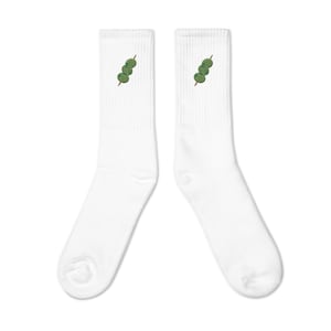 May include: A pair of white socks with a green and brown skewer of round green objects embroidered on each sock.