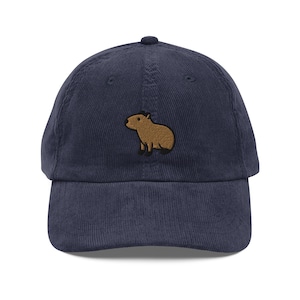 May include: A navy blue corduroy baseball cap with an embroidered brown capybara on the front.