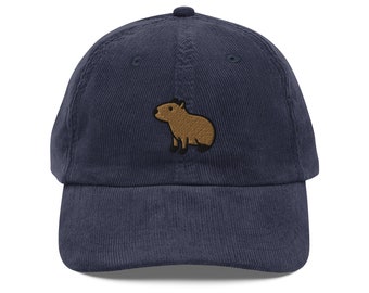 May include: A navy blue corduroy baseball cap with an embroidered brown capybara on the front.