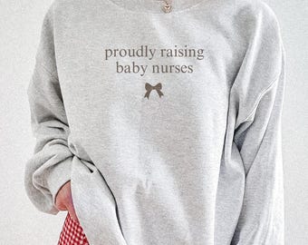 Camiseta "Criando Bebês Enfermeiras" para Educadoras de Enfermagem, Mãe Enfermeira, Instrutora Clínica, Professora de Enfermagem, Camiseta Divertida para Preceptora de Enfermagem.