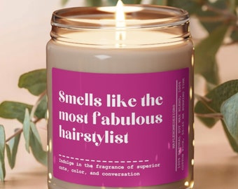 May include: A pink and white candle with the text "Smells like the most fabulous hairstylist" and "Indulge in the fragrance of superior cuts, color, and conversation".