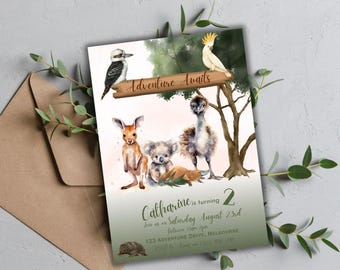 Op de afbeelding: Een groene en witte uitnodigingskaart met een aquarel-illustratie van Australische dieren. De tekst op de kaart luidt "Adventure Awaits" en "Catharine wordt 2 jaar".