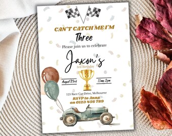 May include: A white invitation with a gold and black checkered flag design. The text reads "Can't Catch Me I'm Three" and "Jaxon's 3rd Birthday". The invitation includes a cartoon race car, balloons, and a trophy.