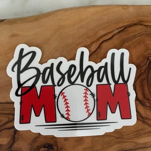 以下が含まれることがあります： 白地に黒文字で「Baseball Mom」と書いてあり、中央に赤い野球ボールが描かれたステッカーです。