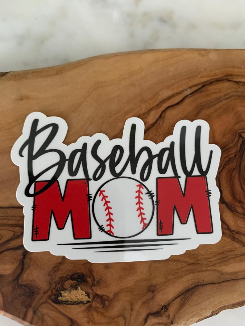 以下が含まれることがあります： 白地に黒文字で「Baseball Mom」と書いてあり、中央に赤い野球ボールが描かれたステッカーです。