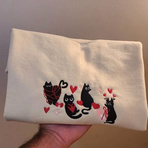 バレンタインの黒猫刺繍スウェットシャツ、刺繍クルーネック猫、バレンタインデーセーター、猫愛刺繍デザイン、xoxoセーター