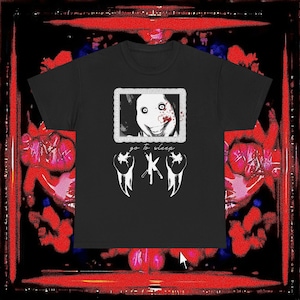 Könnte beinhalten: Ein schwarzes Kurzarm-T-Shirt mit einem Grafikdruck eines Gesichts mit weit aufgerissenen Augen und Blutspritzern in einem dekorativen Rahmen. Unter dem Rahmen steht der Text "go to sleep" über einer Grafik mit drei gekreuzten Messern.