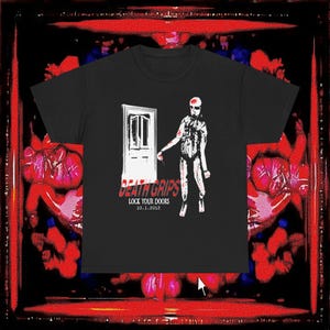 May include: A black t-shirt featuring a white graphic of a door and a figure standing beside it. Below the graphic, the text reads DEATH GRIPS, LOCK YOUR DOORS, and 10.1.2012 in white and red lettering. The design is centered on the chest of the shirt.