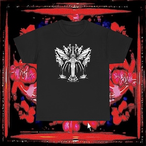 Può includere: T-shirt nero con grafica bianca raffigurante una figura alata e ornata. Il design evoca un tema gotico o fantasy. Lo sfondo è rosso e nero.