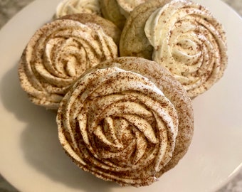 May include: Close-up of a plate of cinnamon sugar cookies with white frosting swirled into a rose shape. The cookies are dusted with cinnamon.