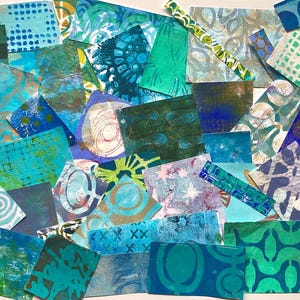May include: A collection of colorful, patterned paper squares in shades of blue, green, and teal. The designs include geometric shapes, swirls, and abstract patterns. The papers are arranged in a layered, overlapping composition.